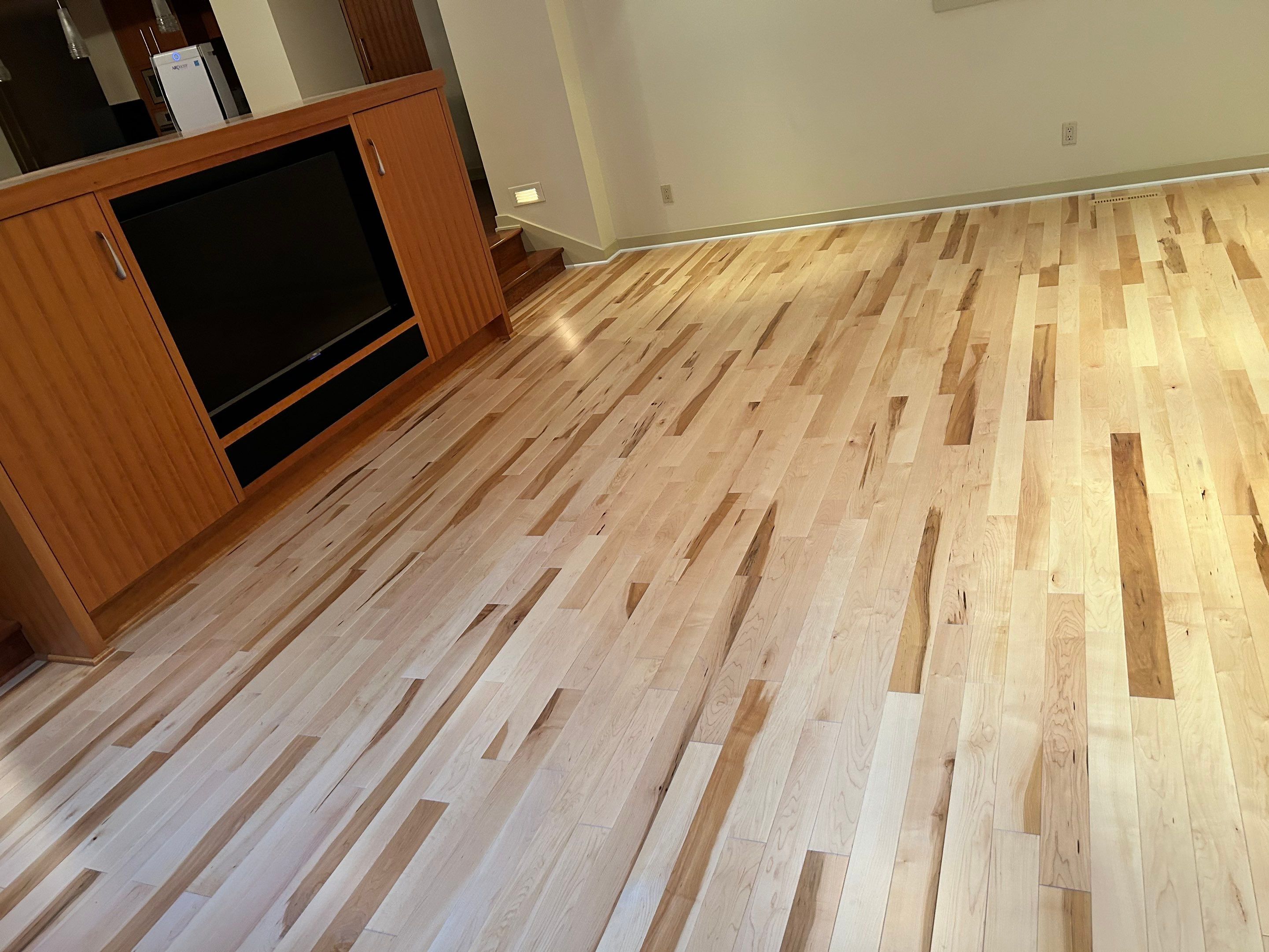 light hardwood flooring in an open room with an entertainment vcenter